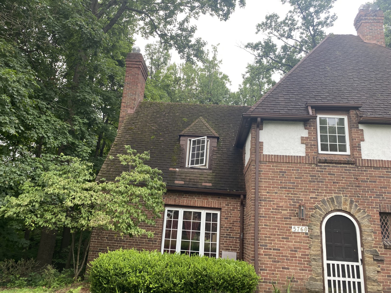 A three-story brick home with a new roof, arched windows and a green lawn