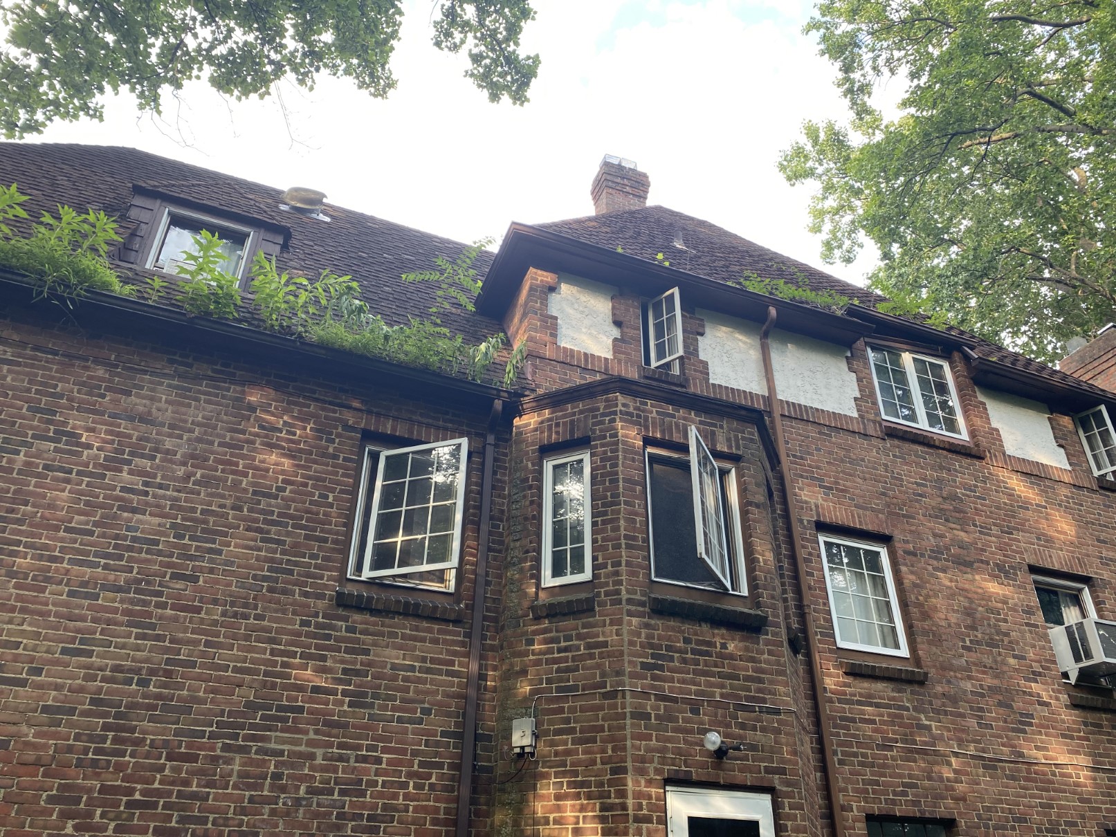 A dark-brick house with a fresh dark roof, side elevation