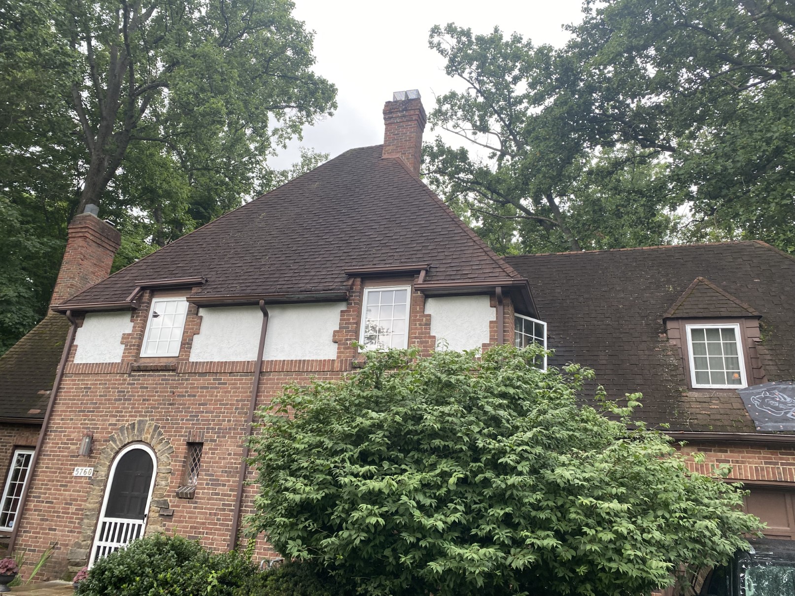 A brick Tudor home with an attached garage and a fresh brown roof