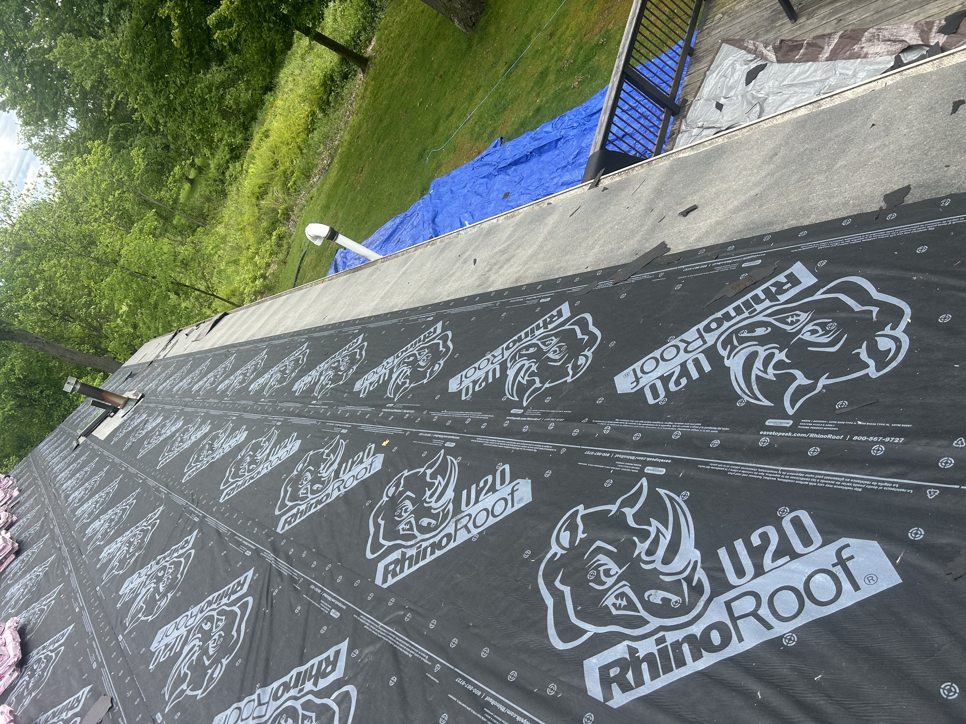A roof deck wrapped in Rhino synthetic underlayment and a blue tarp during a project