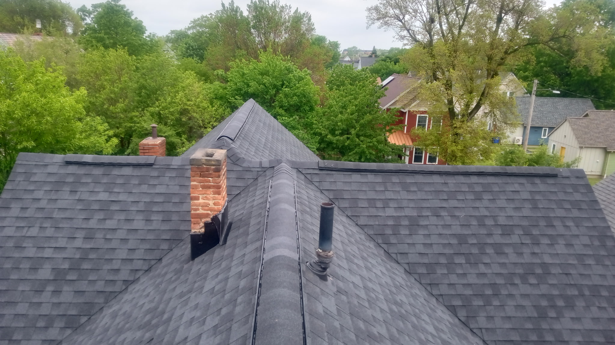 A new grey shingle roof and brick chimney along the ridge line