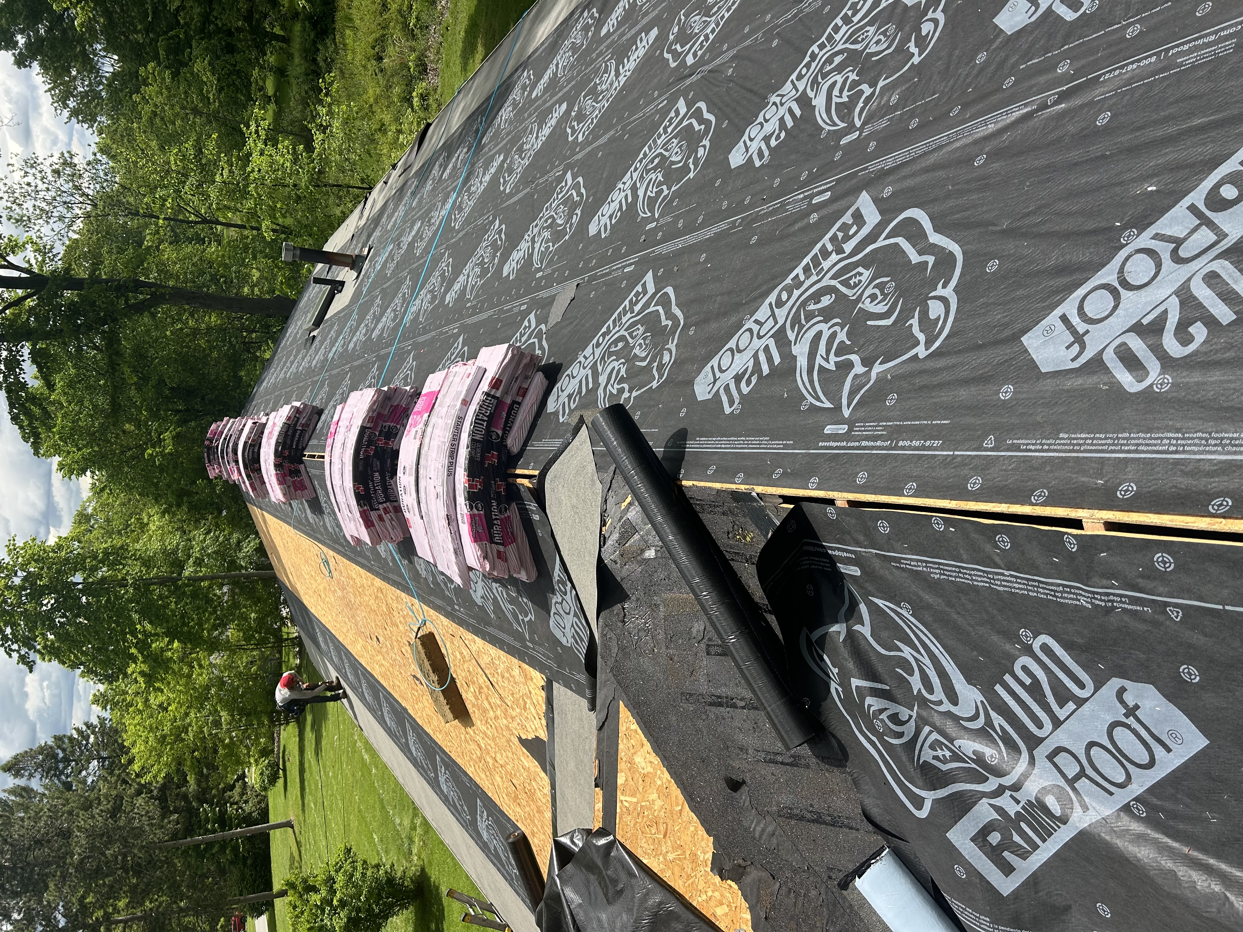 A roof with new underlayment, drip edge and bundles of shingles staged for install