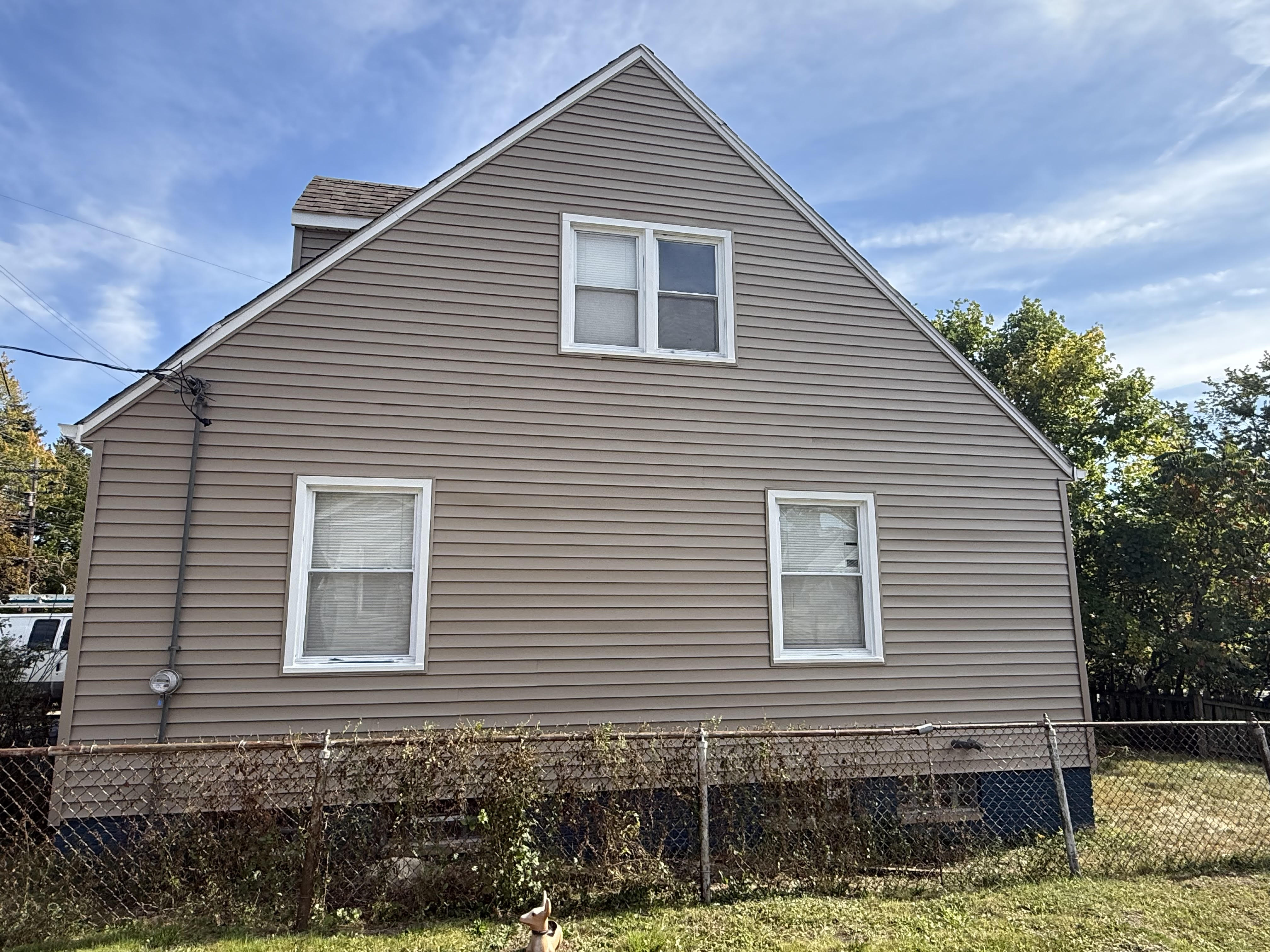 A grey-and-tan sided home with a covered front porch in autumn