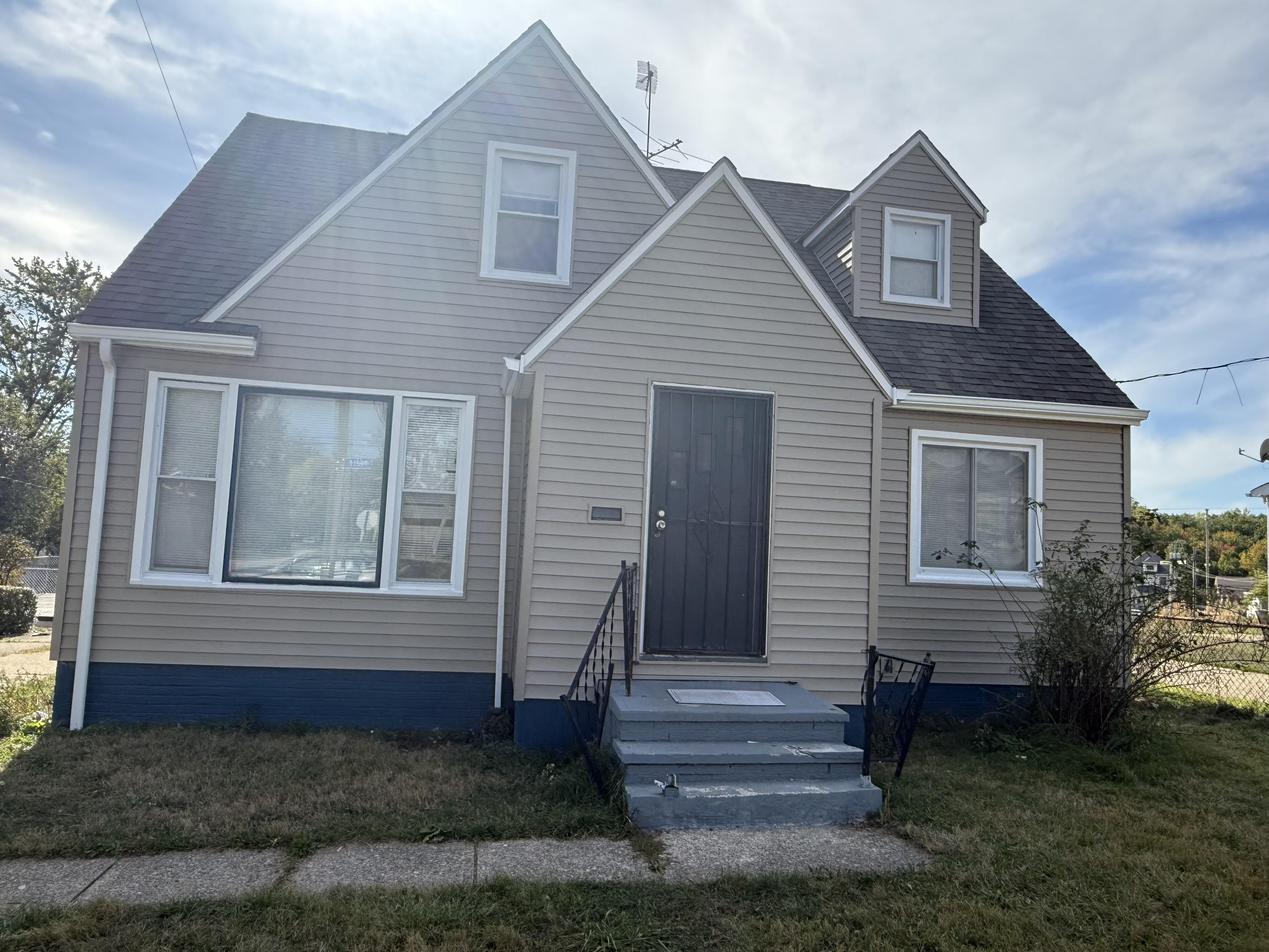 A white-and-grey sided home with blue foundation trim and a front stoop